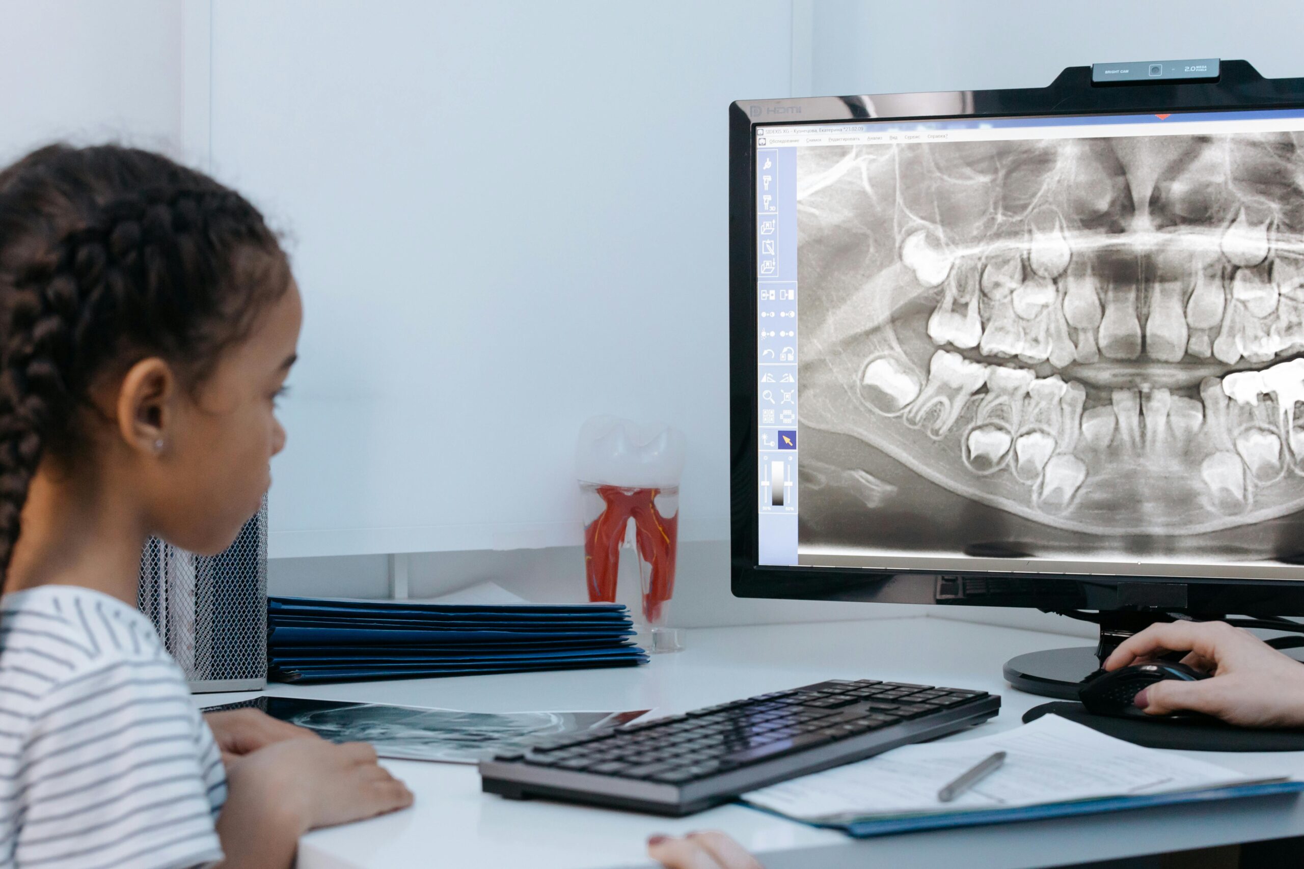 A child observes dental x-ray on a computer screen during a dental check-up in a clinic.